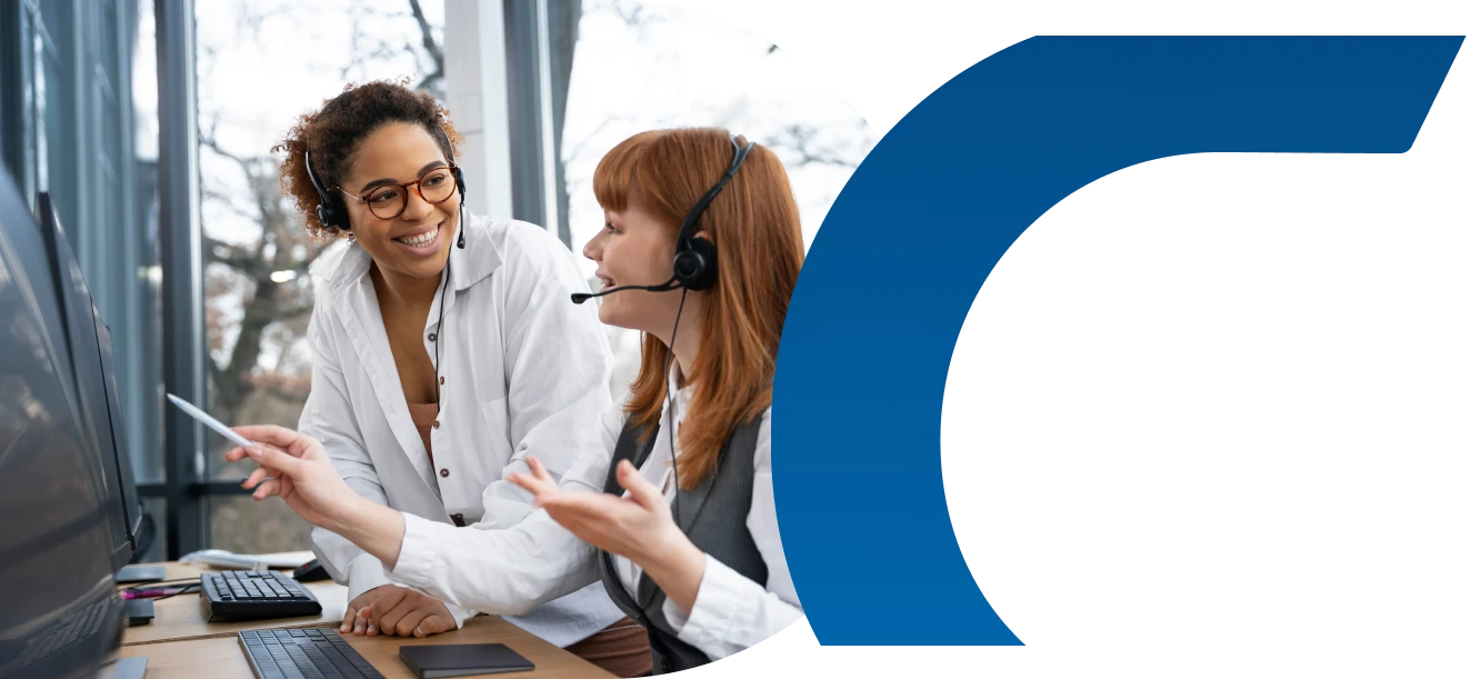 Duas mulheres usando fones na frente do computador conversando e sorrindo